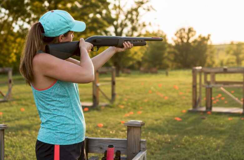 Woman beginner aiming laser clay shotgun outdoors