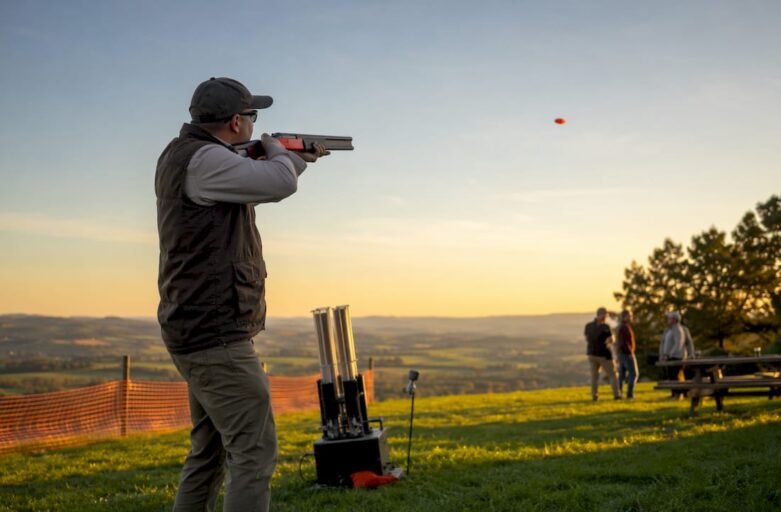 Man aiming laser gun at clay targets outdoors