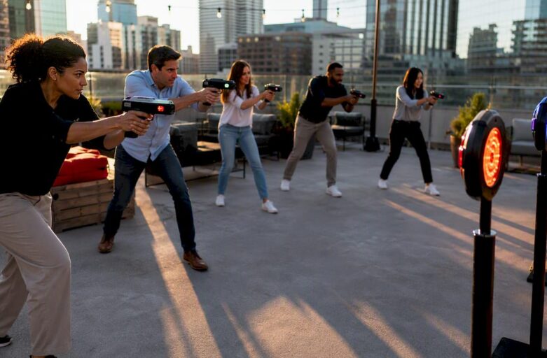 Diverse corporate team shooting lasers outdoors