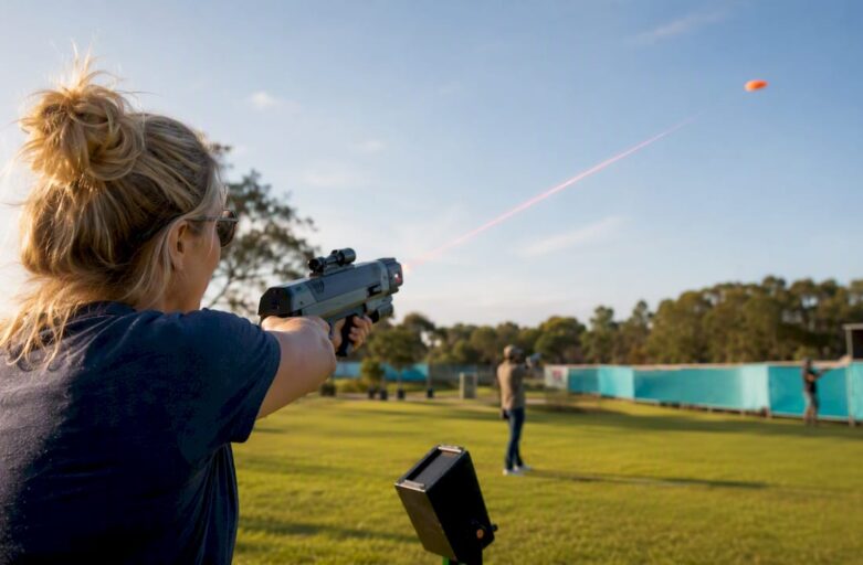 Participant aiming laser gun at clay target indoors
