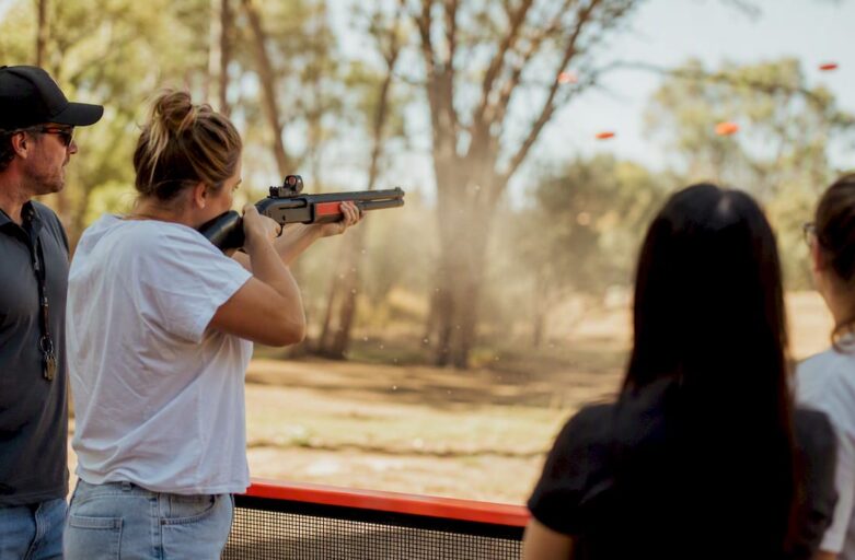 Participant aiming laser clay shotgun at flying target indoors