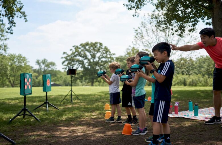 Children aiming laser shooting props at targets outdoors