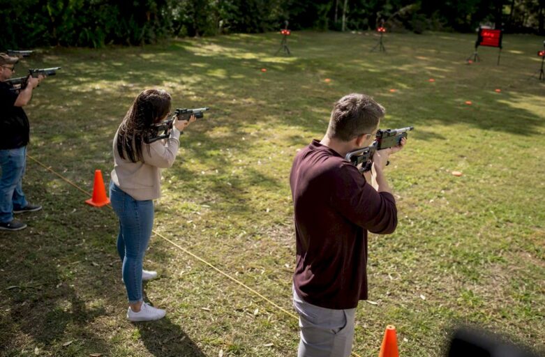 Corporate team shooting laser clay targets outdoors