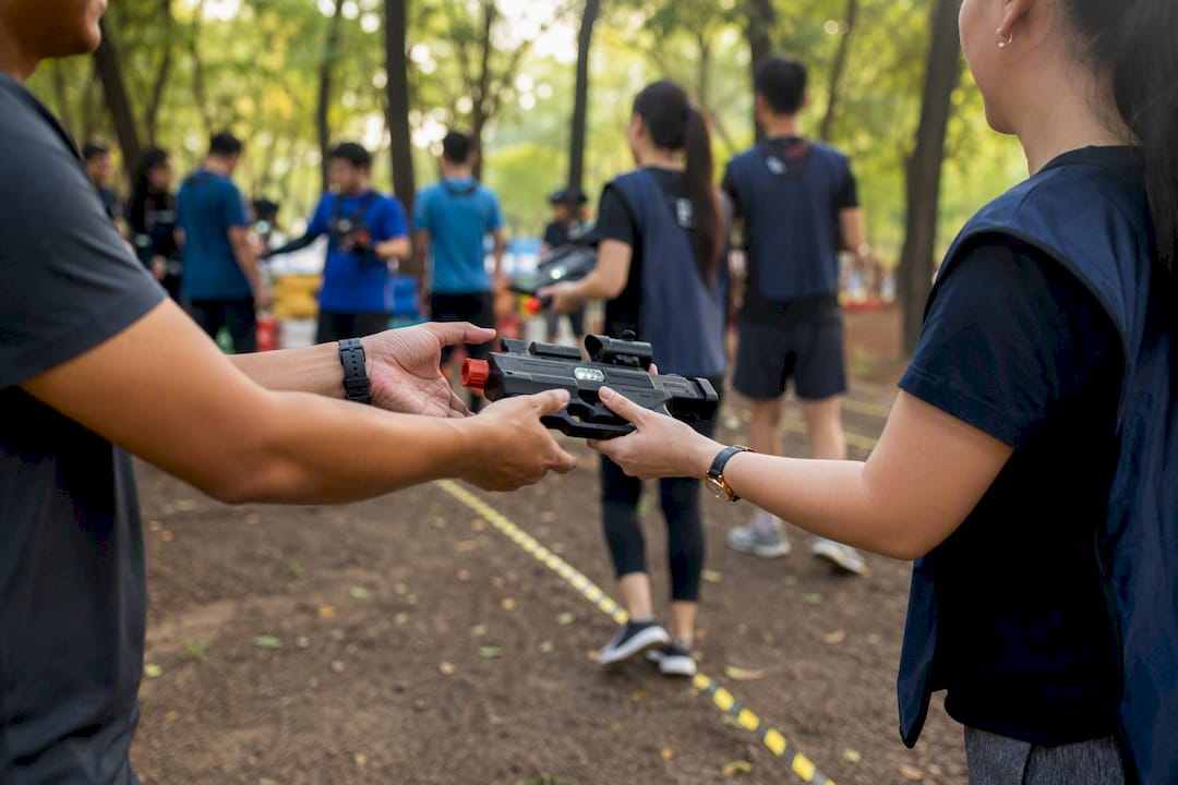 Corporate team handing off laser shooting device during rotation