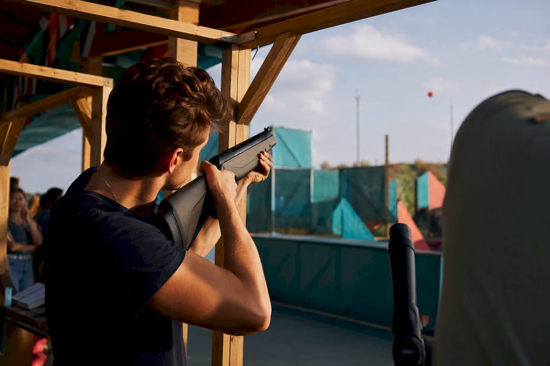 Young adult aiming laser clay gun indoors
