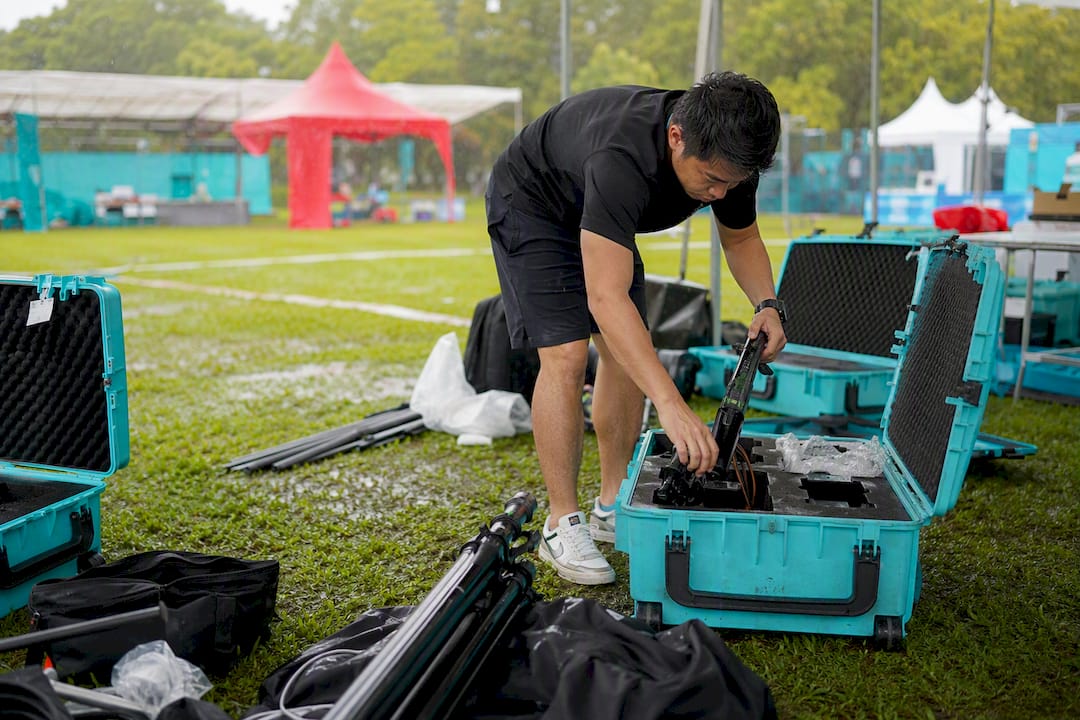 Hands packing laser clay gear in wet outdoor venue