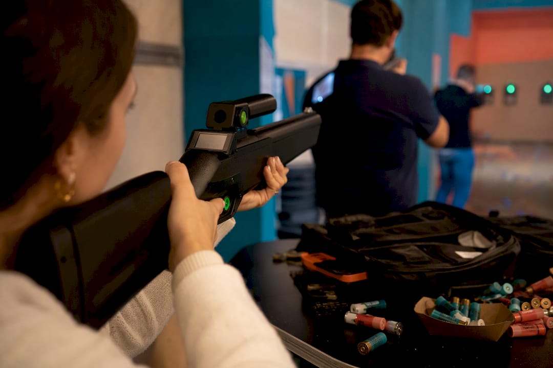 Hands aiming laser clay shooting devices indoors