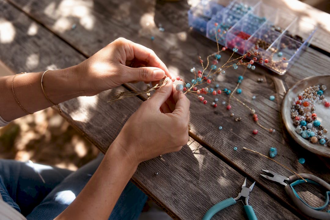 Hands threading beads on wire branches