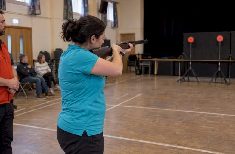 Participant taking a laser clay turn indoors